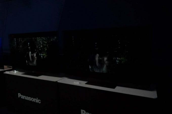 Två svarta Panasonic-TV-apparater står på bord i mörker och visar scen i Dolby Vision IQ