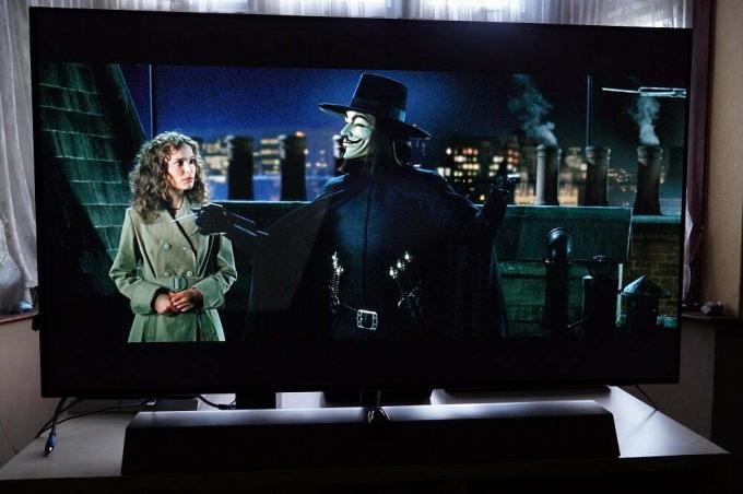 En svart Philips OLED935 står på et bord og viser en scene fra Vendetta